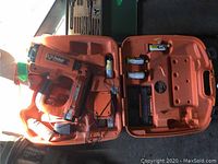 Open Paslode framing nailer kit with nailer, batteries and fuel cells visible in orange case