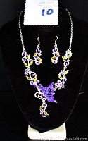 Full view of necklace and earrings displayed on black velvet bust stand.