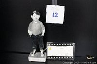 Front and side view of the Spanky figurine showing figure standing with hands in pockets, signed base, and certificate of authenticity in front.