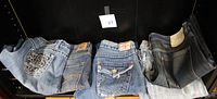 Five pairs of jeans laid out showing variety of brands and washes