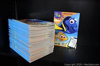 Stack of 48 Disney Finding Dory Color and Play coloring books showing spines and front cover of one book facing forward on shelf.