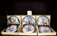 Three pairs of porcelain plates with colored and black and white designs, arranged side by side in original boxes.