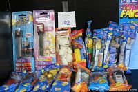 Photo of 15 new, sealed PEZ candy dispensers featuring multiple character styles and packaging, arranged against a black background.