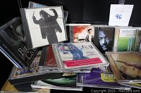Display of numerous CD cases stacked and overlapping, showing artists and soundtracks cover art.