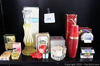 Seven vintage Avon fragrance items arranged, showing various bottles, boxes, and decorative scent items including candlestick bottle and figurine pomander.