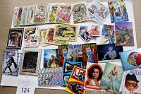 Overview photo of assorted vintage collectible stickers and trading cards laid out on a surface, showing variety of designs and themes.