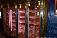 Full front view of four glass-door refrigerator section showing all four doors, interior shelves and lighting