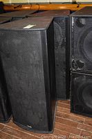 Front and left side view of Mach speaker showing black enclosure and metal grille