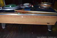 Side view of pool table body with cues and signage on top