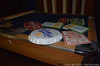Stacked signs on pool table including Coors Banquet oval, Steam Whistle bottle cap, Elvis Fans Parking and others
