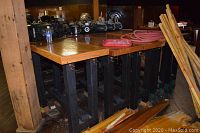 Five wooden tables with oak tops and black painted frames stacked in a row, hooks visible on side frames
