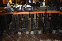 Five wooden tables in a row showing tops, metal legs and side hooks