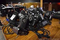 Ten moving head lights piled on wooden tabletop
