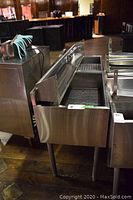 Front view of commercial bar sink showing basin, perforated drain insert and integrated speed rails