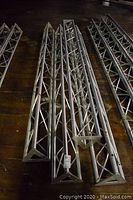 Four aluminum triangular truss towers laid on wooden floor
