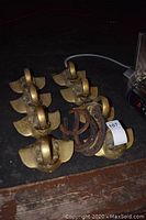 Eight brass elephant head mounts and pile of six rusted horseshoes on black surface