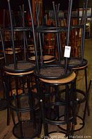 Stacked bar stools showing black metal frames and round wooden seats