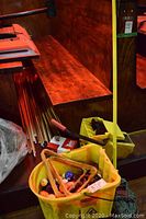 Yellow mop bucket and ringer bucket containing billiard balls and two wooden triangle racks placed inside the mop bucket.