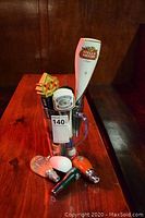 Clear glass pitcher holding multiple beer tap handles including Stella Artois, Creemore Springs, Pilsner and a star-shaped handle