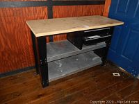 Full front view of work table showing MDF top, metal frame, metal shelves, and two drawers