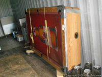 Pool table on dollies, red felt side with Molson Canadian bottle graphic visible, yellow straps securing table upright