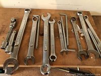 Various socket wrenches laid out on a wood surface showing assortment of sizes and types.
