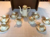 Full set of porcelain tea set including teapot, cups, saucers, creamer, and sugar bowl displayed on table.