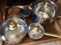 Three pots with glass lids and gold-tone knobs, one lid is perforated