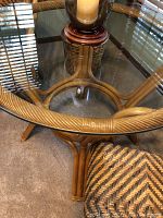 Close-up of rattan table frame and glass top edge showing rattan wrapped detail and circular base structure.