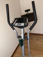 View of the upper part of the elliptical trainer showing the dual handlebars, console, and cup holder