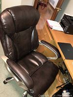 Front and top view of the dark brown leather office chair showing padded seat, backrest, and armrests.