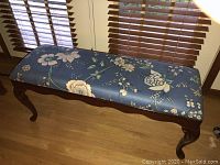 Full view of the bench showing floral upholstered seat and cherry wood frame with cabriole legs.