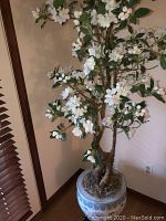 Full view of large artificial cherry blossom tree with white flowers and green leaves indoors.