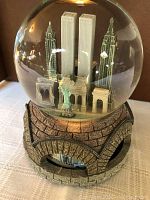 Front view of snow globe showing New York landmarks inside including Twin Towers and Statue of Liberty.