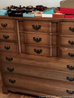 Front view of the maple chest of drawers showing multiple drawers with dark metal handles and various jewelry boxes on top.
