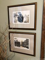 Photo showing two framed prints hung vertically on wall, featuring street lamp and street scenes