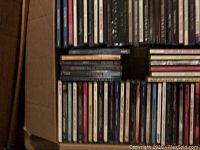 Photo showing a packed cardboard box filled with a large number of CDs organized horizontally and vertically.