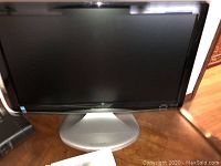 Full front view of Sharp 19-inch LCD TV standing on a wooden surface with screen off and silver base visible.