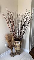 Full view of large ceramic vase with decorative branches and small glass vase with dried grasses near base
