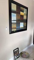 Large square abstract wall art on wall showing grid of colorful squares in black frame