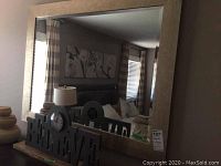 Large framed mirror with thick rustic wood frame, reflecting a room interior