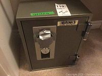 Front view of Brinks home safe showing label, dimensions, and lock area covered with tape.