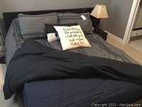 Full view of made bed showing dark wood frame, headboard, bedding and attached nightstand