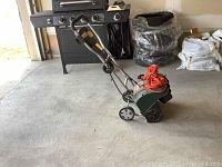 Full side view of YardWorks electric snow shovel with extension cord attached and folded handlebar, placed on concrete floor.
