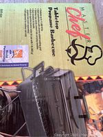 Box label showing Master Chef brand, product name Tabletop Propane Barbecue, and image of the black grill with folding legs.