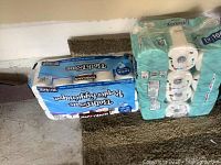 Overall view of both packages side by side on the floor, showing unopened condition.