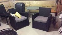 Both wicker armchairs side by side with gray seat cushions and one decorative pillow in storage area
