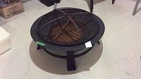 Front view of assembled fire pit with cooking grate and tools