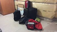 Photo showing all bags lined up on the floor: Samsonite suitcases, black knapsacks, red soft cooler, red duffel bag