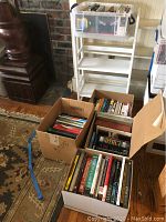 Overall view showing white shelf and five boxes of books arranged in front